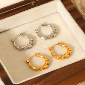 Gold and silver star hoop earrings displayed in a luxury wooden velvet jewelry box