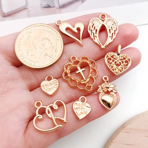 Golden heart charms for jewelry making shown with a 1-dollar coin for scale