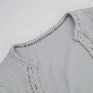Close-up of light gray knitted bodysuit featuring crew neck stitching and ribbed texture