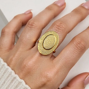 Close-up of golden hollow ring featuring a hammered texture and minimalist line design