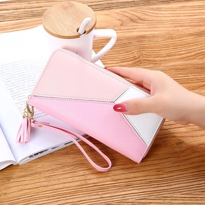 Detail of a pink contrast patchwork wallet with tassel and wristlet on a table
