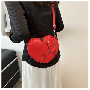 Detailweergave van een rode hartvormige leren tas met zilveren metalen klinknagels