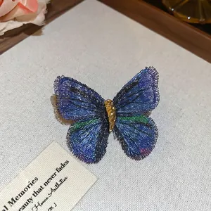 Elegant butterfly brooch with blue and green woven wire wings on a vintage rustic fabric
