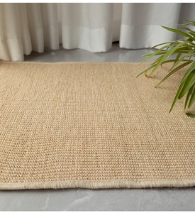 Close-up of natural sisal rug texture with woven fibers on a grey tile floor