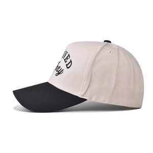 Dettaglio del cappello da baseball bicolore con ricamo laterale su sfondo bianco