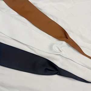 Flat lay of brown, white and black leather corset belts with detailed skin texture