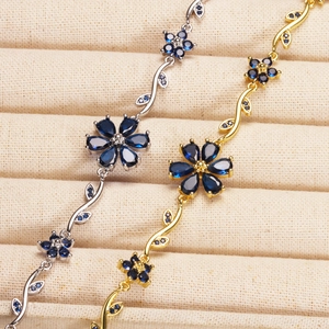 Detailed macro view of five-petal floral leaf bracelets with blue pear-cut gemstones