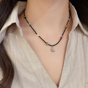Detail of beaded gemstone necklace with conch shell pendant on a striped shirt