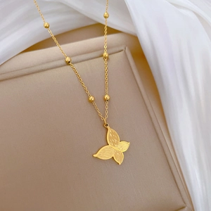 Collier papillon doré texturé avec chaîne à billes présenté sur un coffret à bijoux