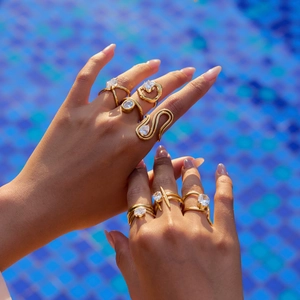 18K gold plated stainless steel rings with zircon stones on a model hand by a pool