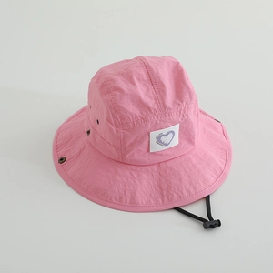 Detail of pink quick-dry sun hat showing heart patch and adjustable chin strap cord