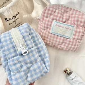 Vista dettagliata di trousse trapuntate con cuciture a cuore e motivo a scacchi