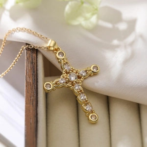 Detail shot of a gold-plated cross necklace with marquise and round zircon stones