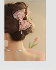 Detail of pink tulle bow hair claw with pearl tassel and rhinestones on hair