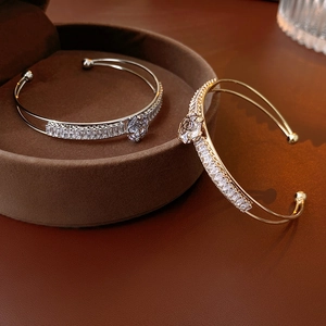 Detail of silver and gold rose open bracelets with zircon inlay on a velvet jewelry box