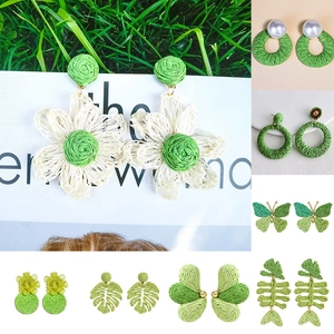 Macro shot of green and white raffia earrings featuring floral and fishbone patterns