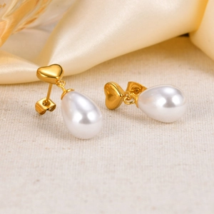 Detail shot of heart-shaped gold studs and white teardrop pearl drops on silk background