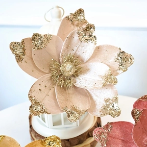 Close-up of velvet magnolia artificial flower with golden glitter petals and stamens