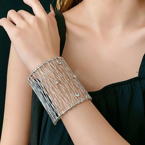 Detailed view of silver mesh cuff bracelet with embedded crystals on model wrist