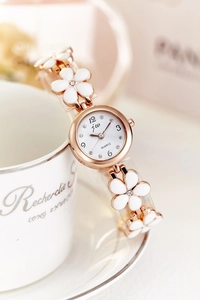 Detail of rose gold quartz watch featuring white floral links and crystal indices