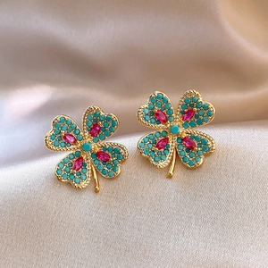 Macro des boucles d'oreilles trèfle en or avec perles turquoise et pierres rubis