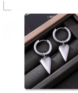 Detailed shot of polished silver heart pendants on hoop earrings inside a jewelry box