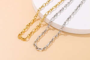 Detailed view of textured oval link chains in gold and silver finish on white platform