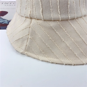 Gros plan sur un chapeau bob beige avec franges rayées et texture en coton et lin