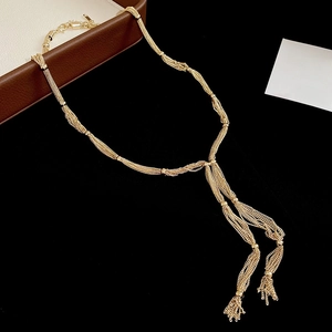 Detail of a layered gold tassel necklace with bead accents on a black background