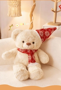 Detail eines cremefarbenen Teddybären mit roter Weihnachtsmütze und Schneeflockenschal