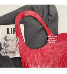 Detail of red crocodile pattern shoulder bag with a stylish integrated curved handle