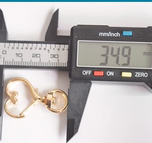 Macro view showing heart-shaped alloy lobster clasp measured at 34.9mm on digital caliper