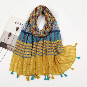Detail of bohemian printed scarf featuring mustard yellow patterns and blue tassel fringe