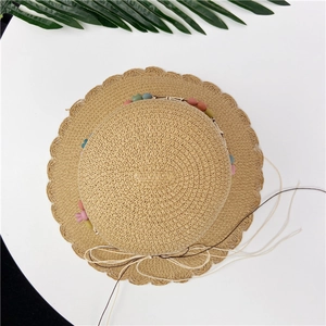 Detail of woven straw sun hat with scalloped wavy edges and colorful bead decoration