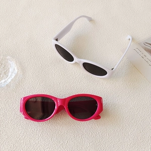 Flat lay of vintage oval sunglasses in white and rose pink colors on a textured surface