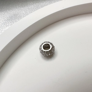 Macro shot of S925 silver spacer bead with cubic zirconia on white tray with silk backdrop