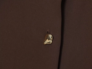 Détail de la robe midi marron foncé avec bouton doré de forme organique texturé