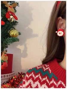 Détail d'une boucle d'oreille Père Noël portée par un mannequin avec un sapin de Noël festif