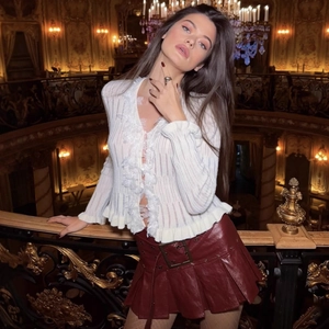 Cardigan in maglia bianca con volant in pizzo e gonna a pieghe in ecopelle color bordeaux