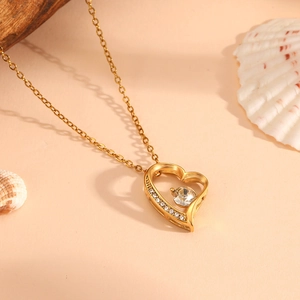 Macro detail of a gold heart pendant with a large crystal center and small zircon accents