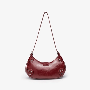 Detail shot of red crocodile texture leather bag with silver rivets and sleek crescent shape