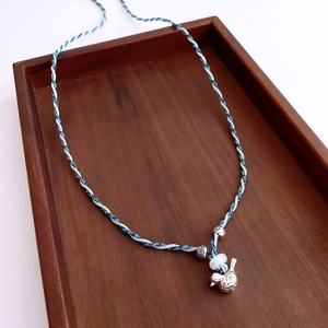 Détail du collier en corde tressée bleue et blanche avec pendentif oiseau et perles