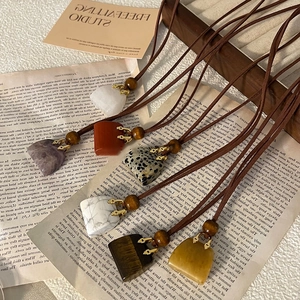 Macro view of assorted natural stone heart pendants with rustic gold clasps and brown cords