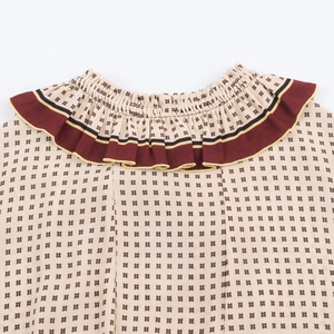 Detail of ruffle neckline with geometric print and contrast trim on a chiffon dress