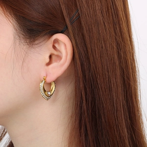Gros plan de boucles d'oreilles cœur dorées avec strass portées par un mannequin