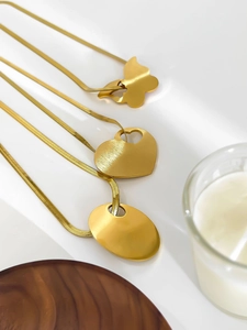 Detailed close-up of golden snake chain necklaces with butterfly and heart pendants