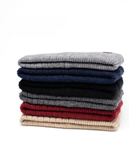 Close-up of six stacked ribbed knit beanies showing thick texture in multi-colors
