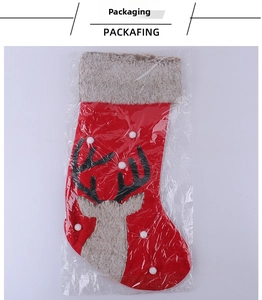 Close-up of red Christmas stocking with plush reindeer head detail in plastic packaging