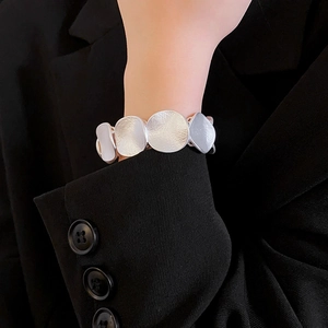 Close-up of matte silver metal chain bracelet with textured round links on a model