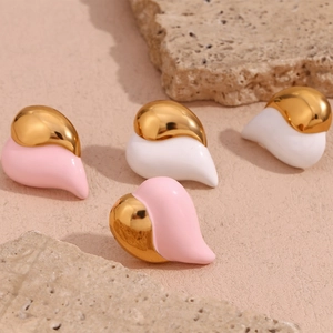 Macro detail of heart-shaped gold plated earrings with pink and white enamel on stone